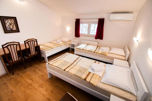 Habitación con 3 camas y mesa. en Rooms Kenedy, en Međugorje