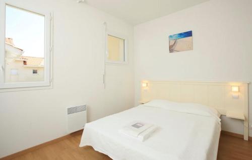 ein weißes Schlafzimmer mit einem Bett und einem Fenster in der Unterkunft Résidence Indigo II - Ocean Plage Résidences in Biscarrosse-Plage