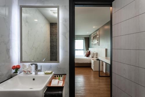 a bathroom with a sink and a room with a bed at Cmor by Recall Hotels SHA Extra Plus in Chiang Mai