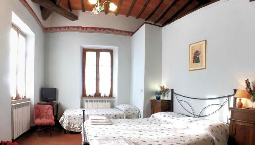 a bedroom with two beds and a tv and two windows at Agriturismo Le Stringaie in Montepulciano Stazione