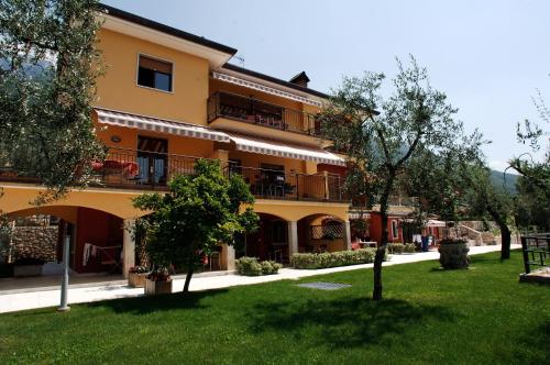 a large yellow building with trees in front of it at Villa Due Leoni - Residence in Brenzone sul Garda