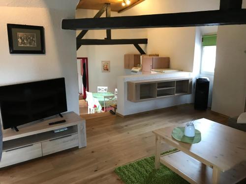 a living room with a flat screen tv and a table at Gästehaus Windheim (Karlsruher Denkmal) in Karlsruhe