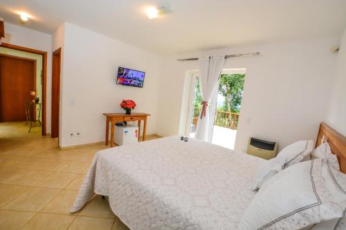 a bedroom with a large white bed and a window at La Réserve Suites in Monte Verde