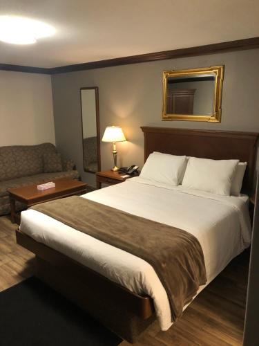 a hotel room with a large bed and a couch at Talbot Trail Inn & Suites in Leamington