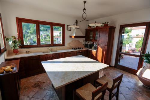a kitchen with a counter and some chairs and windows at Casa Anna a Pietrasanta in Toscana con piscina in Pietrasanta