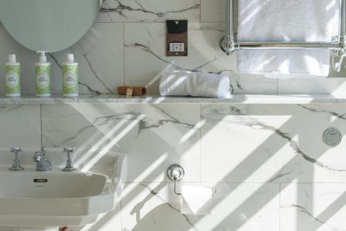 a white bathroom with a sink and a mirror at The White House in Burnham Market