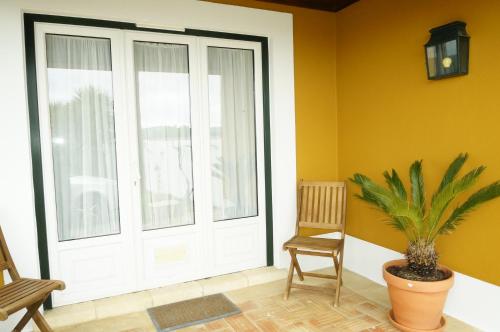 a white door with a plant and a chair at Quinta de São José dos Montes in Ferreira do Zêzere