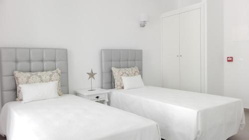 two beds in a room with white walls at Casa do Rio in Alcácer do Sal
