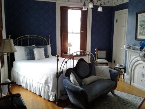 a bedroom with a bed and a chair and a window at Proctor Mansion Inn in Wrentham