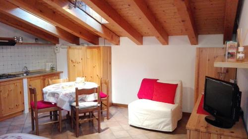 a kitchen with a table and chairs and a television at Sweet Home Casa Vacanze "La Mansarda" in Rovetta