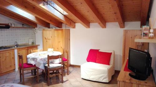 kuchnia ze stołem, krzesłami i telewizorem w obiekcie Sweet Home Casa Vacanze "La Mansarda" w mieście Rovetta