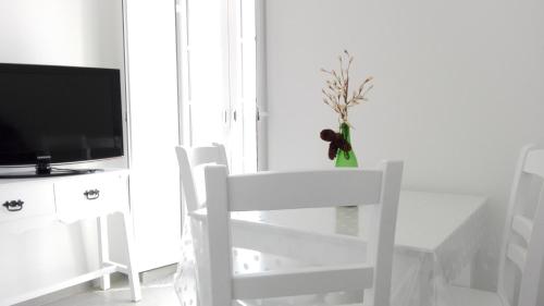 uma mesa branca, uma cadeira branca e uma televisão em Casa do Rio em Alcácer do Sal