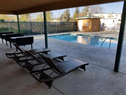 a swimming pool with a group of chairs next to it at Gridley Inn & RV Park in Gridley