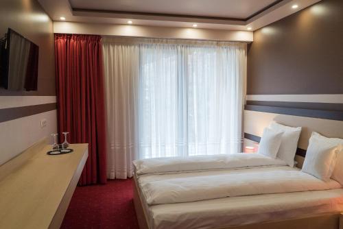 Homorod Hotel في بايلي هومورود: غرفة فندقية بسريرين ونافذة