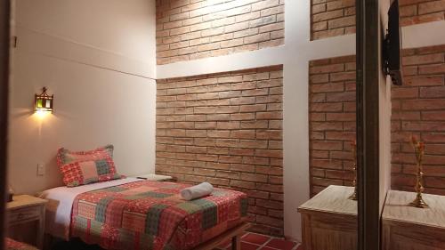 a room with a bed and a brick wall at Villa Mimi in Otavalo