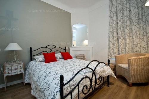 - une chambre avec un lit doté d'oreillers rouges et d'une chaise dans l'établissement Napoléon, à Cannes