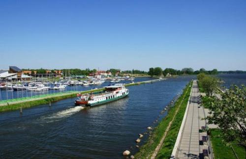 a boat traveling down a river next to a dock at Apartament 4 Żagle in Giżycko