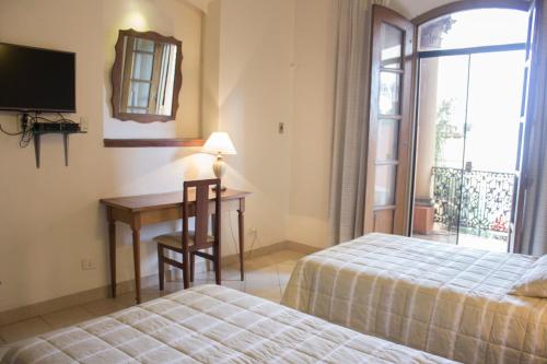 a bedroom with two beds and a desk and a window at Asuncion Palace in Asuncion