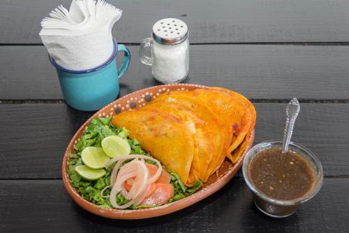 a table topped with a plate of food and a salad at Hotel La Casona de Don Jorge in Colima