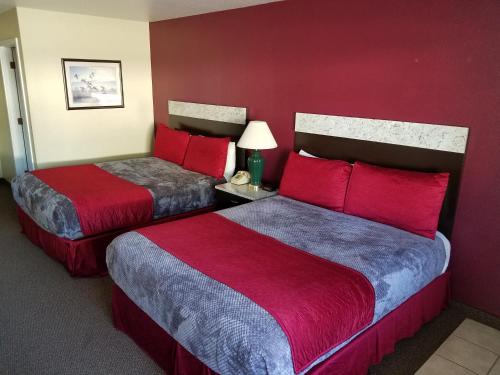 two beds in a hotel room with red walls at Gridley Inn & RV Park in Gridley