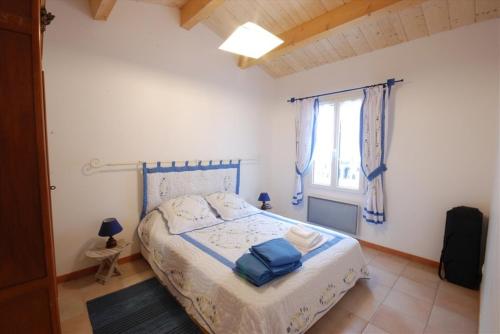 une chambre avec un lit avec des draps bleus et une fenêtre dans l'établissement Le Figuier, au Bois-Plage-en-Ré