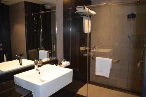 a bathroom with a sink and a shower at Golden Tulip Mandison Suites in Bangkok