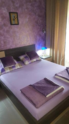 a large bed with purple sheets and pillows on it at Apartman Centar Lux in Budva