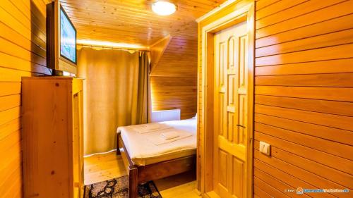 Taverna Ceahlau في دوراو: غرفة صغيرة بسرير في كابينة خشبية