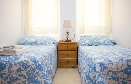 1 dormitorio con 2 camas, vestidor y ventanas en Apartamentos Turísticos Fercomar, en Nerja