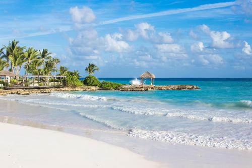 a sandy beach with palm trees and the ocean at Eden Roc Cap Cana in Punta Cana