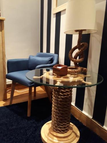 a glass table with a lamp and a blue chair at Aldatzeta Ostatua in Bermeo