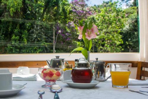 una mesa con un jarrón de flores y un vaso de zumo en Serra Negra Palace Hotel, en Serra Negra