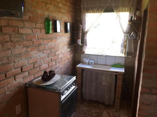 a kitchen with a brick wall and a stove and a sink at Chalé Ibiti in Conceição da Ibitipoca