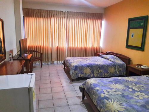 a hotel room with two beds and a desk at Hostal Solar Del Puerto in Machala
