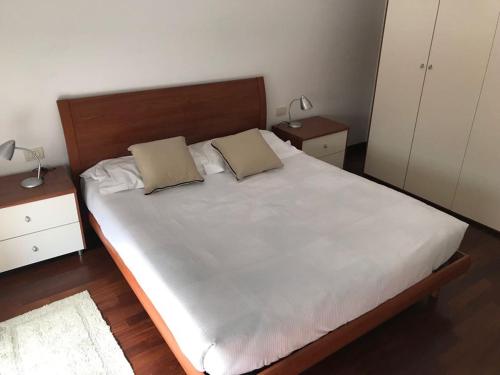 - une chambre avec un grand lit blanc et 2 tables de chevet dans l'établissement Lecco centro - casa indipendente, à Lecco