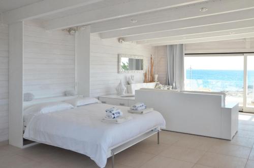 una camera bianca con letto e vista sull'oceano di Casa Dansodà a Torre Lapillo