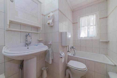 a white bathroom with a sink and a toilet at Villino Guest House in Akrotiri