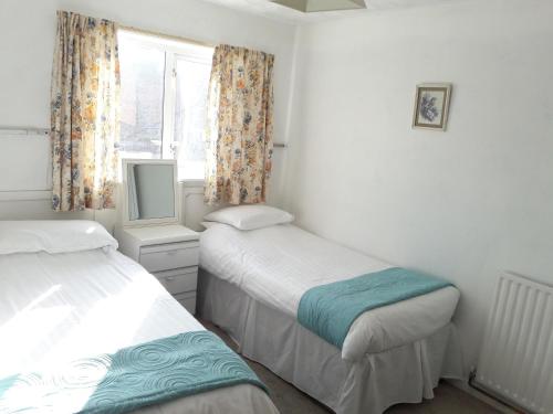 a bedroom with two beds and a window and a tv at Springfield Holiday Apartments in Skegness