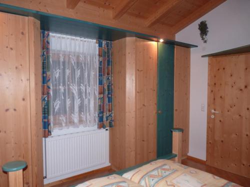 a bedroom with wooden walls and a window at Conny's Ferienwohnungen in Gschnitz