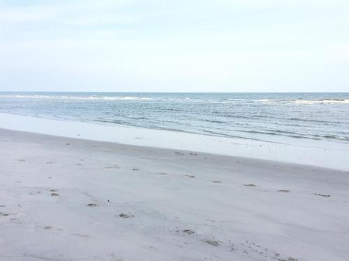 a beach with footprints in the sand and the ocean at The Trust Condo Huahin by Petcharat in Hua Hin