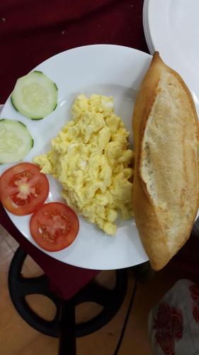 un piatto bianco con uova, un panino e pomodori di Windbell Villa Hoi An a Hoi An