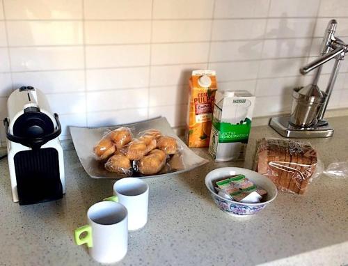 Un mostrador con algo de comida y tazas sobre la encimera. en Luxury Arquillos Vitoria, en Vitoria-Gasteiz