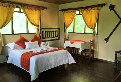 a bedroom with a bed and a table and windows at Suchipakari Amazon Eco -Lodge & Jungle Reserve in Puerto Misahuallí