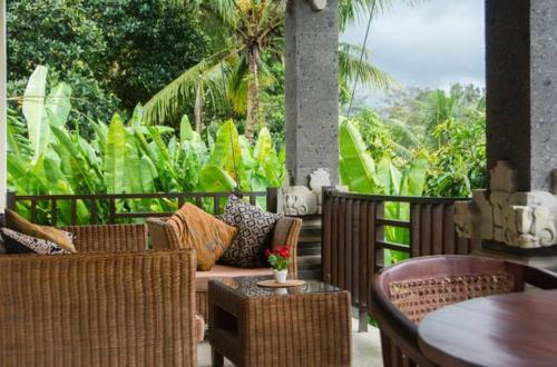 a patio with wicker furniture and a table and chairs at Lily Lane Villas in Ubud