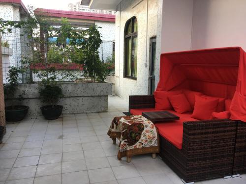 a couch with red pillows sitting on a patio at March Garden next to the Furniture Market in Shunde