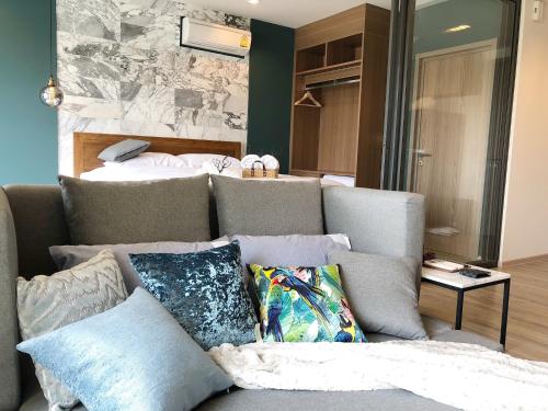 a couch with pillows in a room with a bed at Rain Cha-am Huahin By Sake in Cha Am