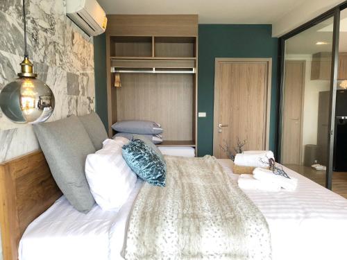 a bedroom with a bed with white sheets and blue pillows at Rain Cha-am Huahin By Sake in Cha Am