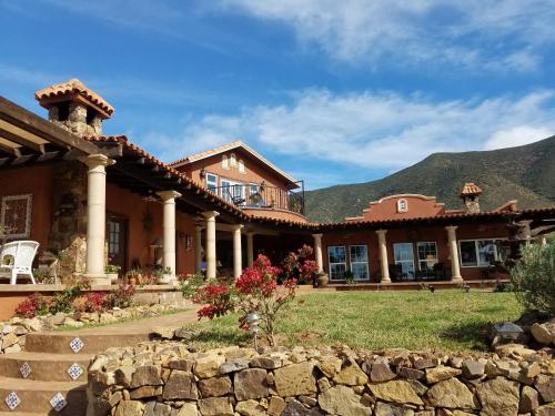 a large house with a stone wall in a yard at Viña Calabria in Valle de Guadalupe