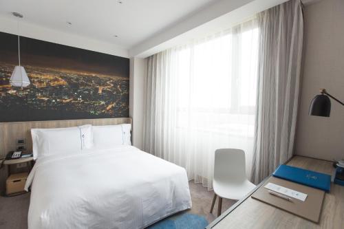 a hotel room with a white bed and a window at Airline Inn - Kaohsiung Station in Kaohsiung