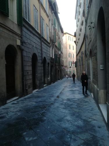 an empty alley with two people walking down the street at Nonna Anna in Siena